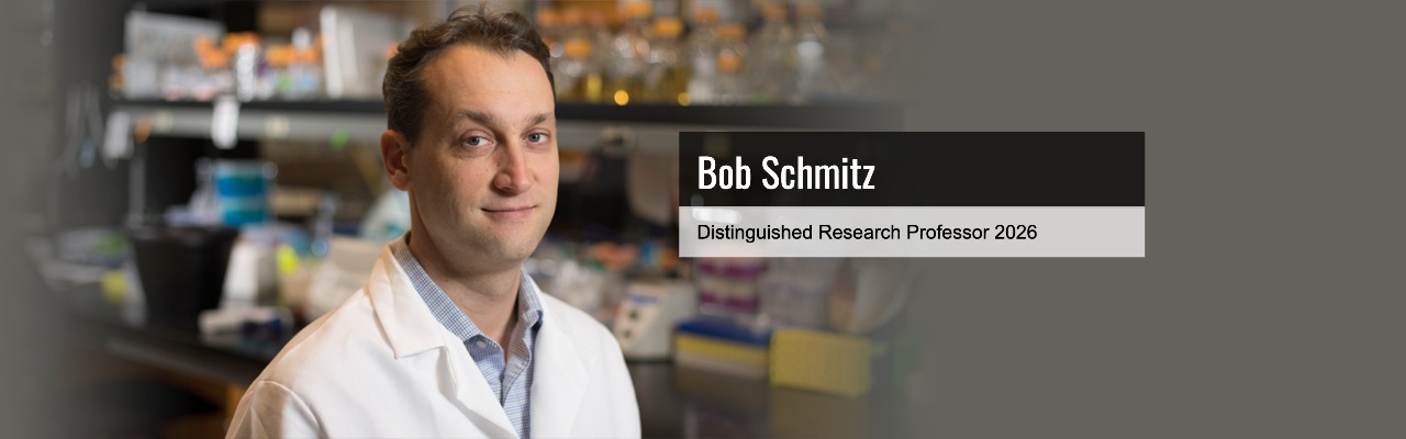 A man in a white lab coat stands in a laboratory. Text overlay reads: Bob Schmitz, Distinguished Research Professor 2026.